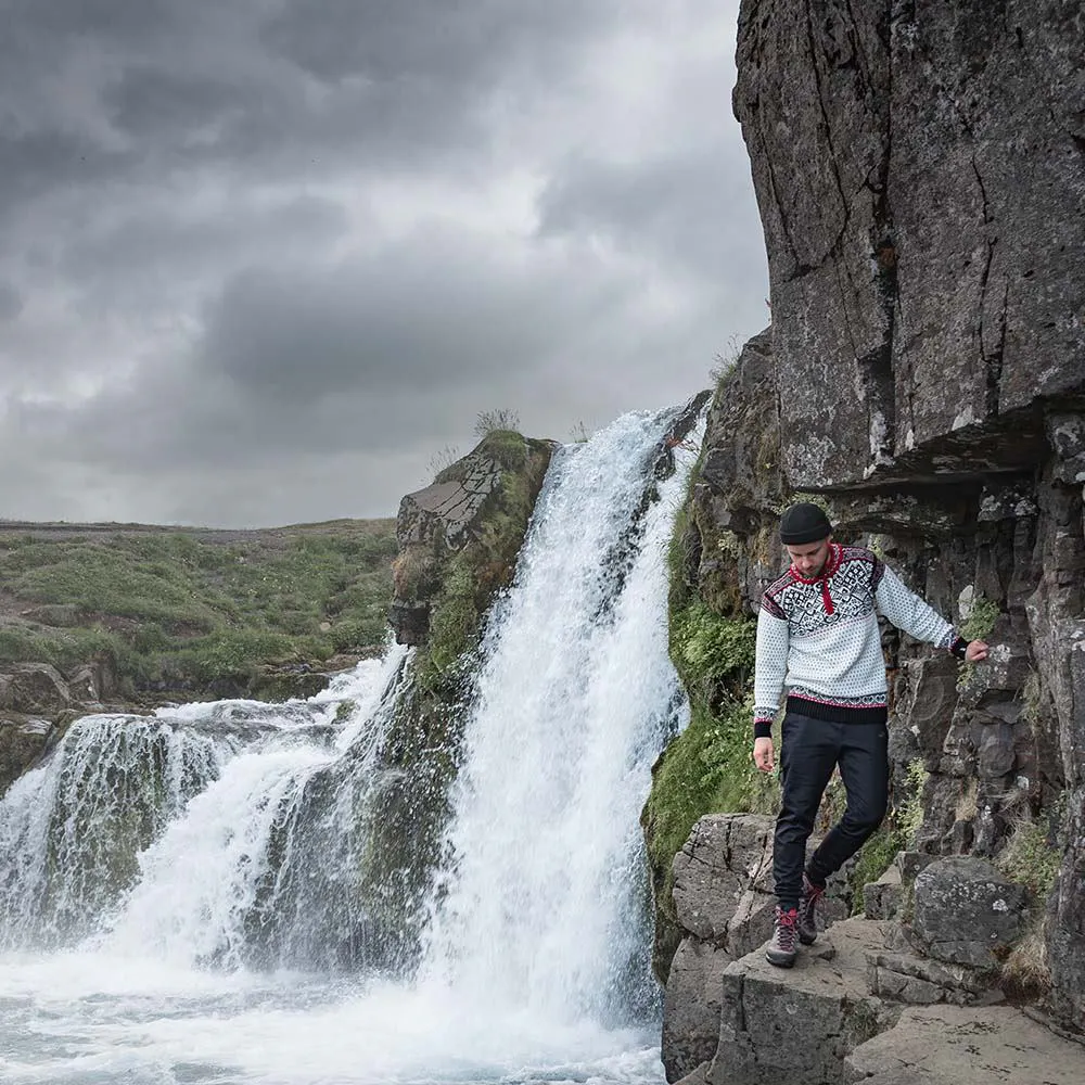 man walking next to waterfall