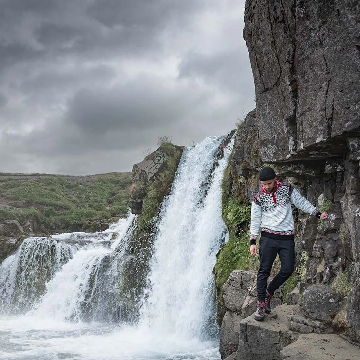 man walking next to waterfall