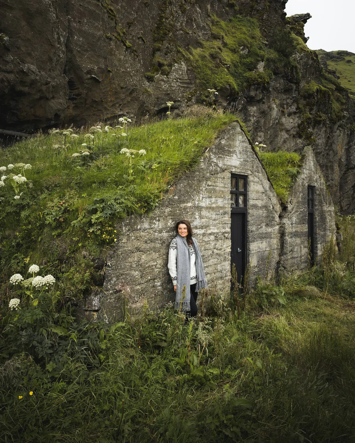 Frau an einem alten Haus mit Grasdach