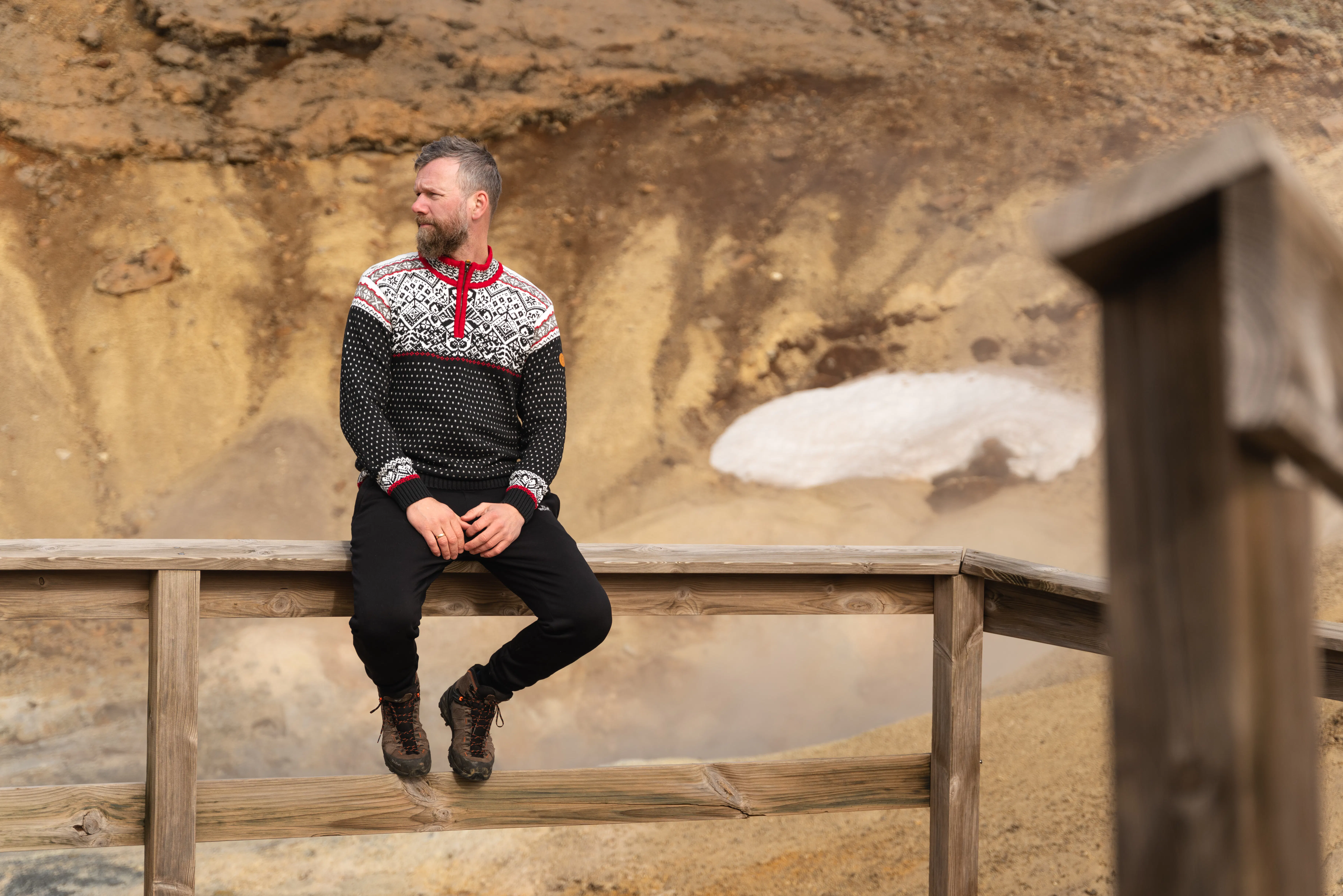man sitting on a fence in hot spring area in Iceland