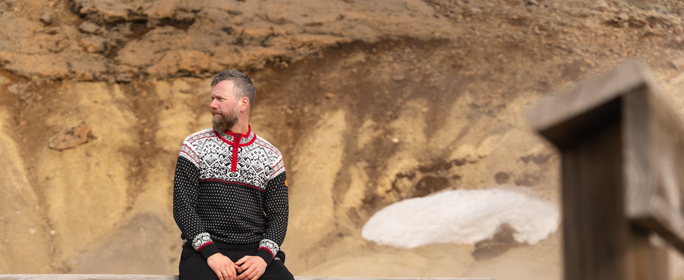 man sitting on a fence in hot spring area in Iceland