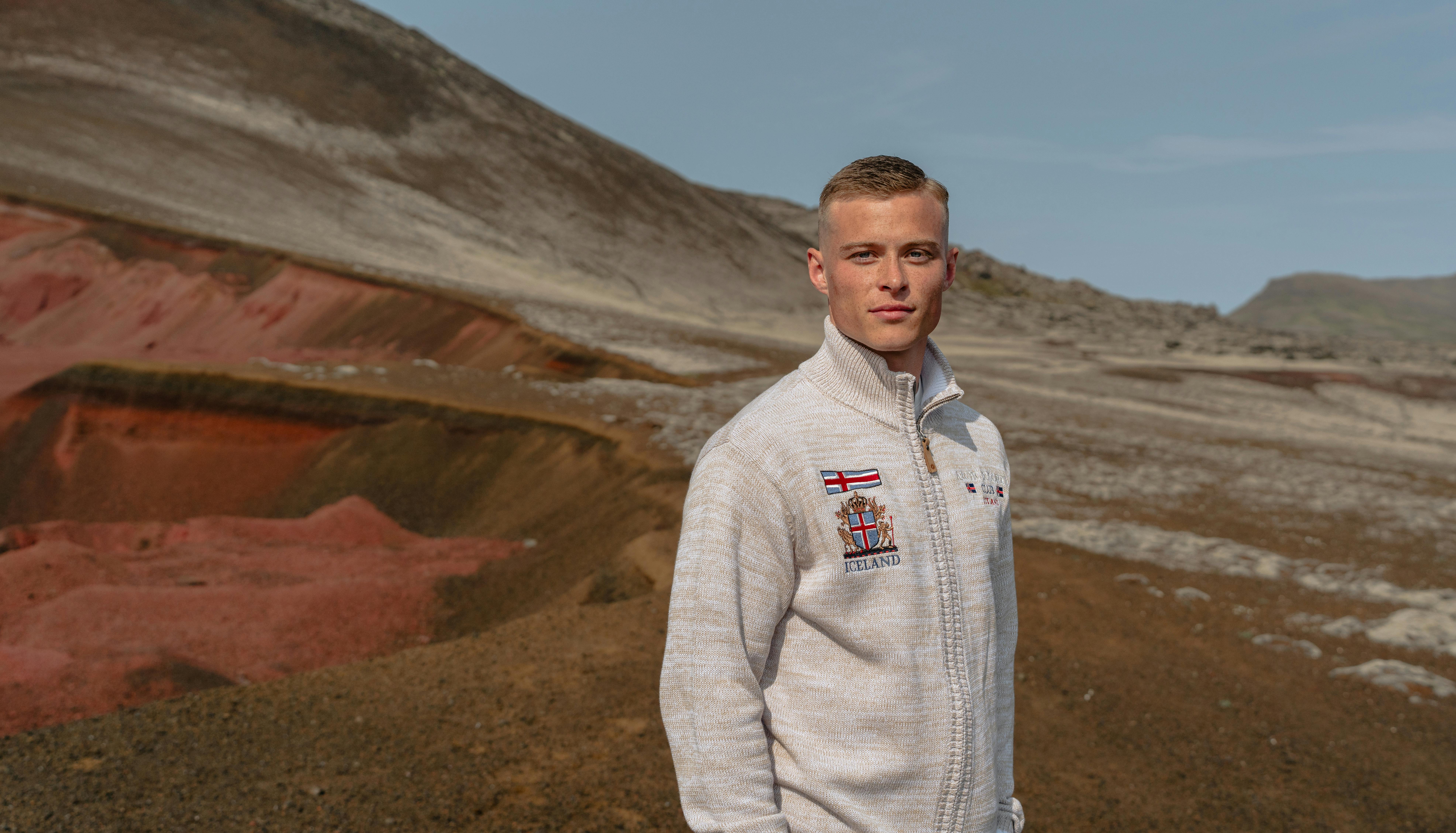 man and red sand mountain behind him