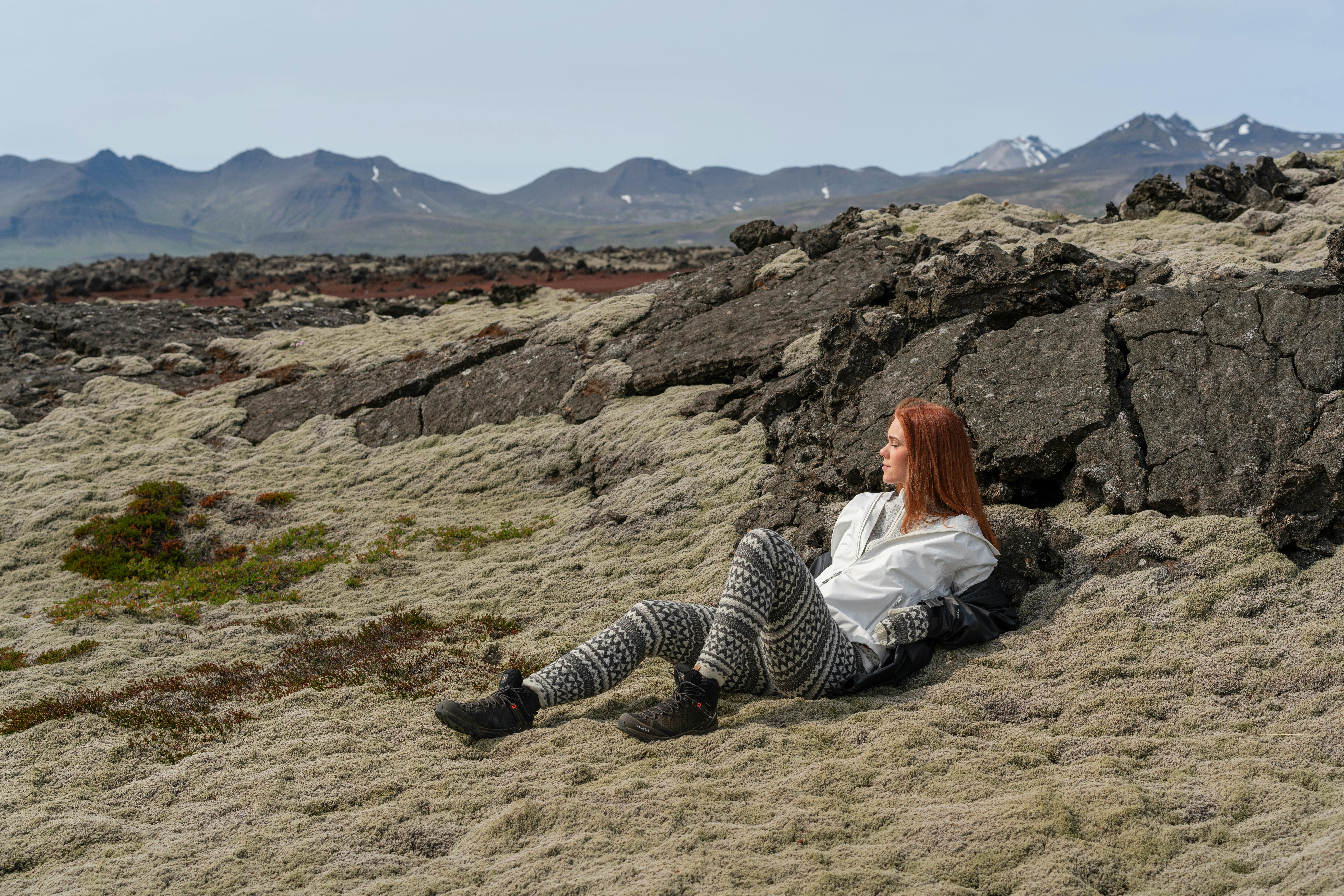 A woman lies in moss, in a lava environment