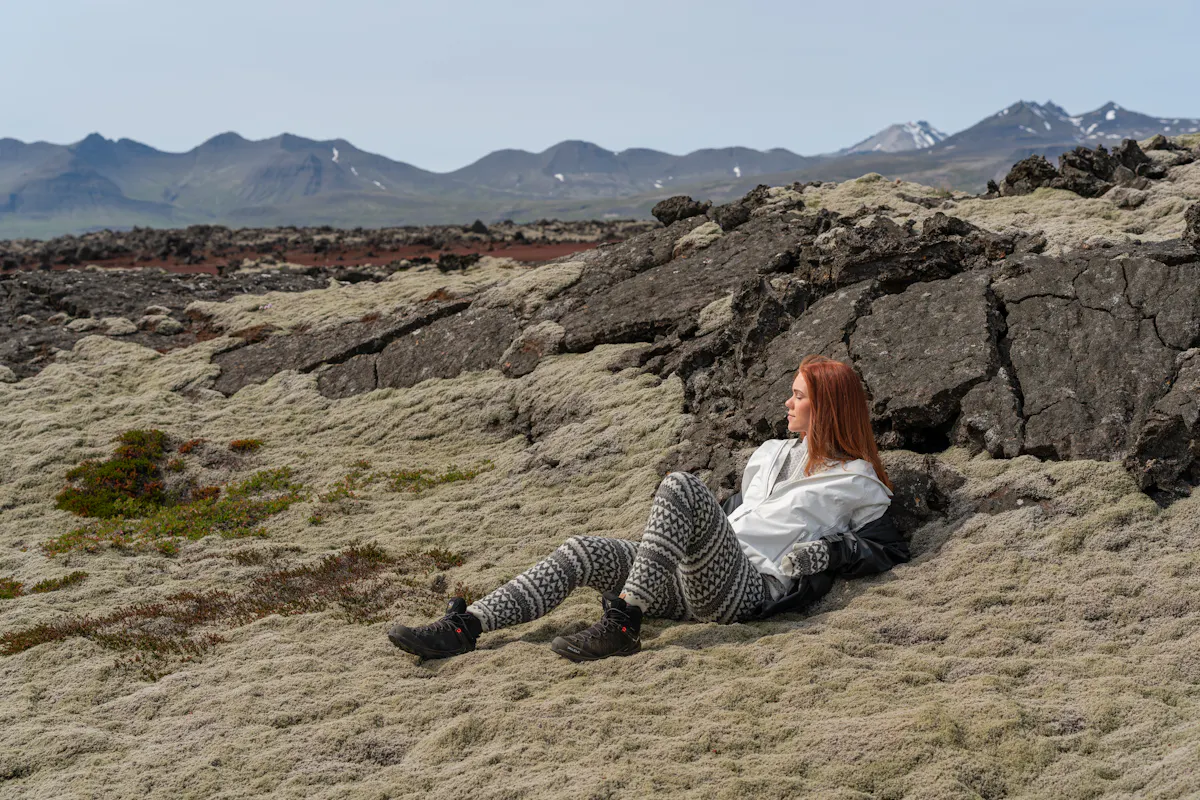 A woman lies in moss, in a lava environment