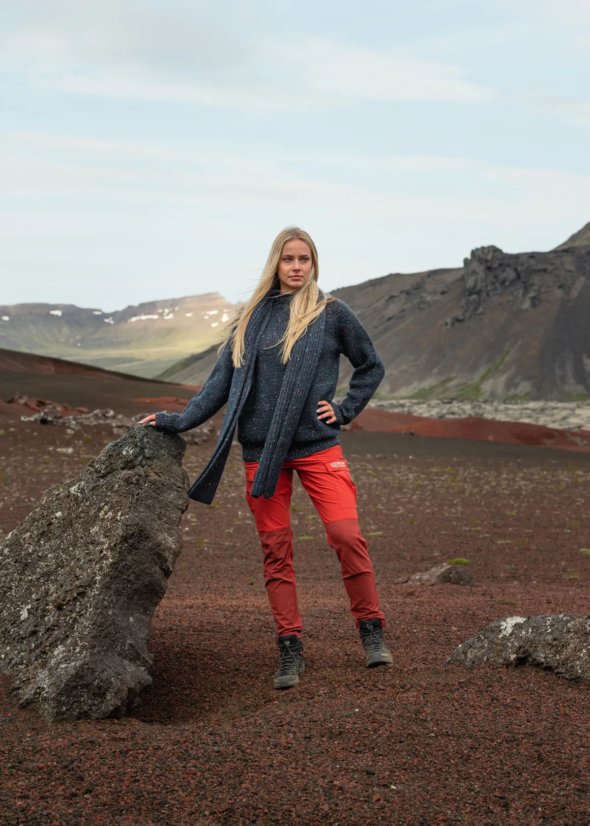 Frau steht an einem großen Felsen