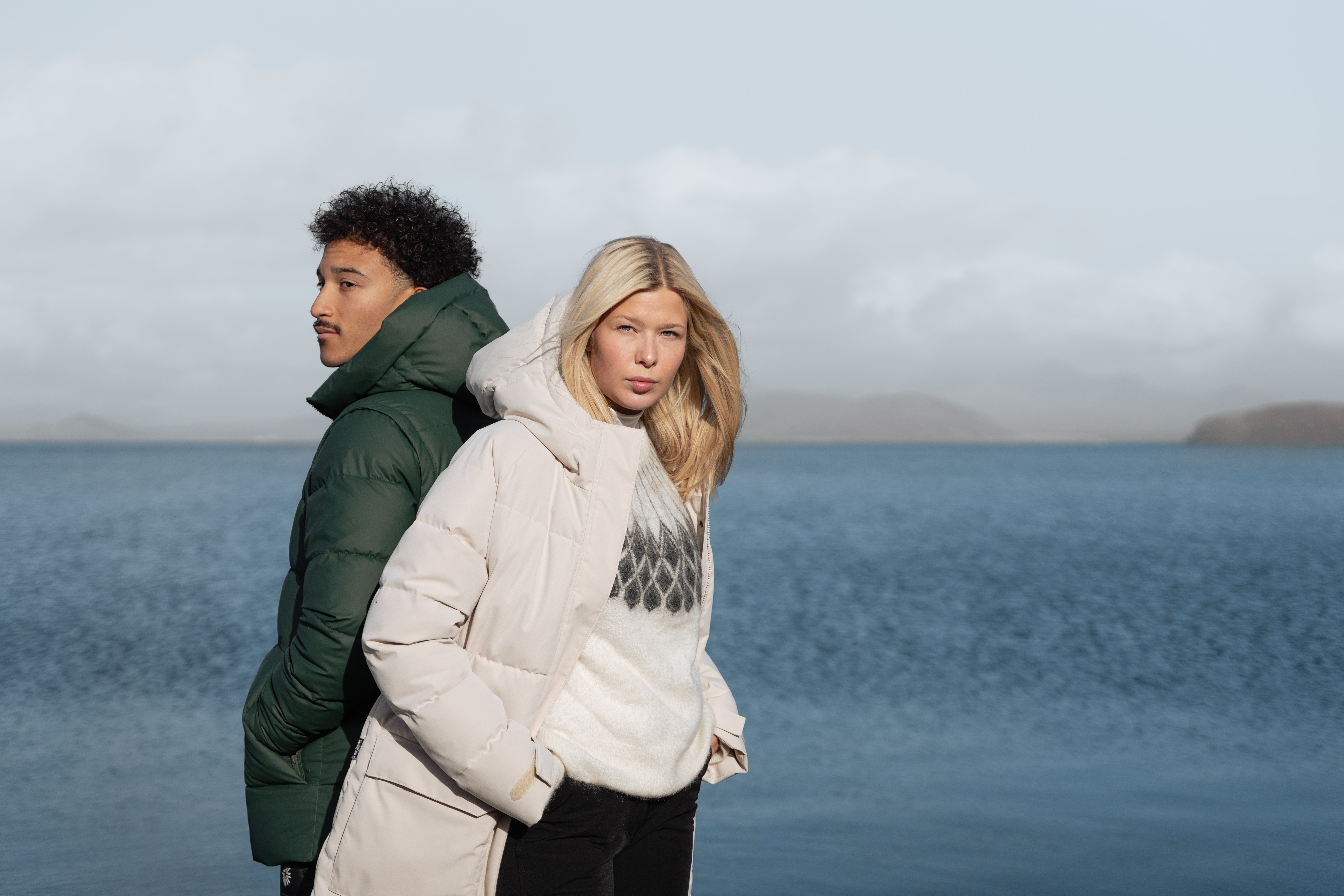 couple wearing warm parka and the sea behind them