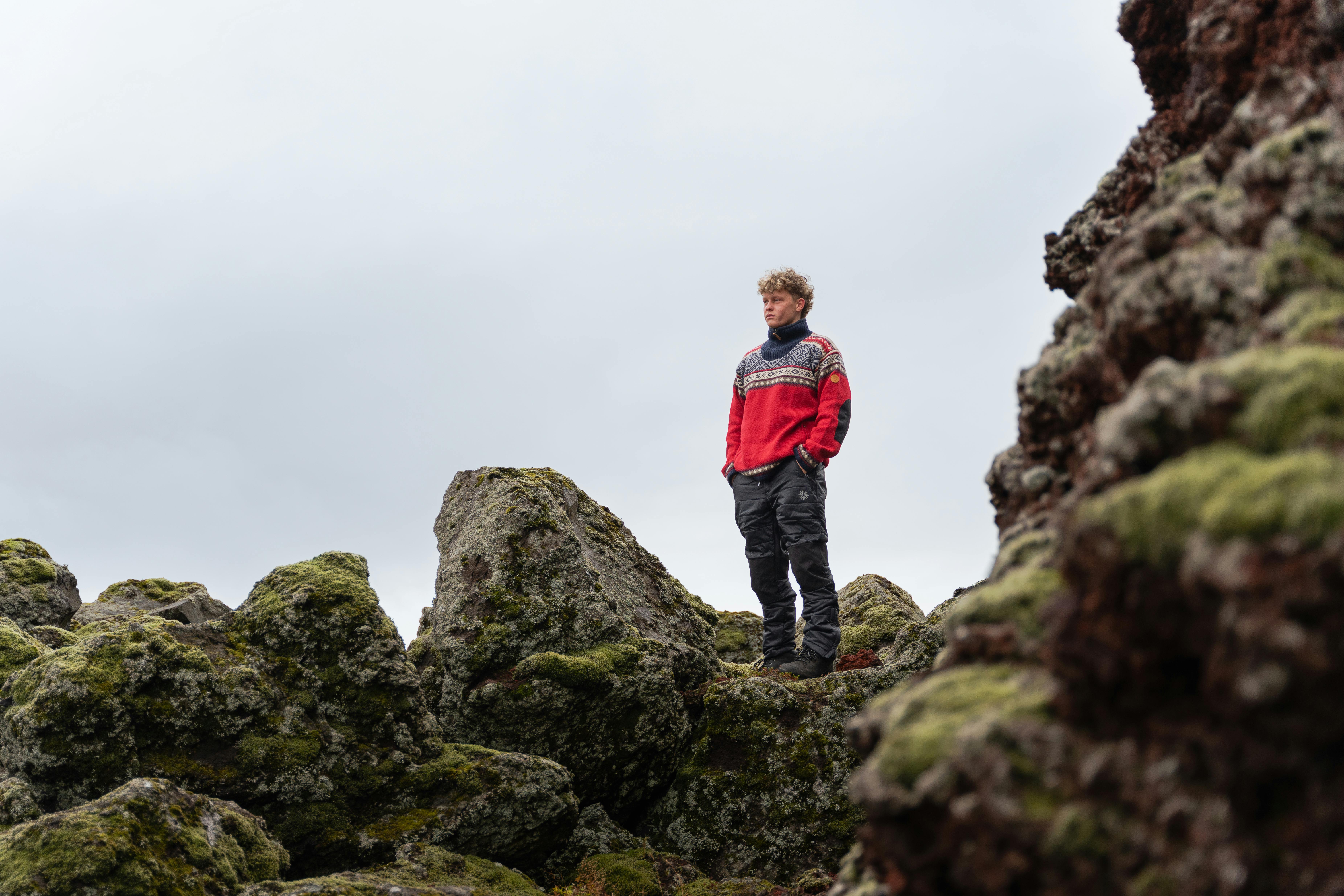 man in lava field wearing Norwegian sweater called Bergen