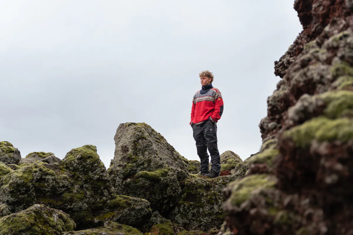 man in lava field wearing Norwegian sweater called Bergen