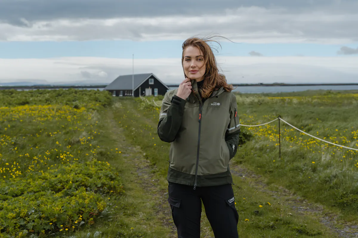 une femme dans le champ et une vieille maison et la mer derrière elle
