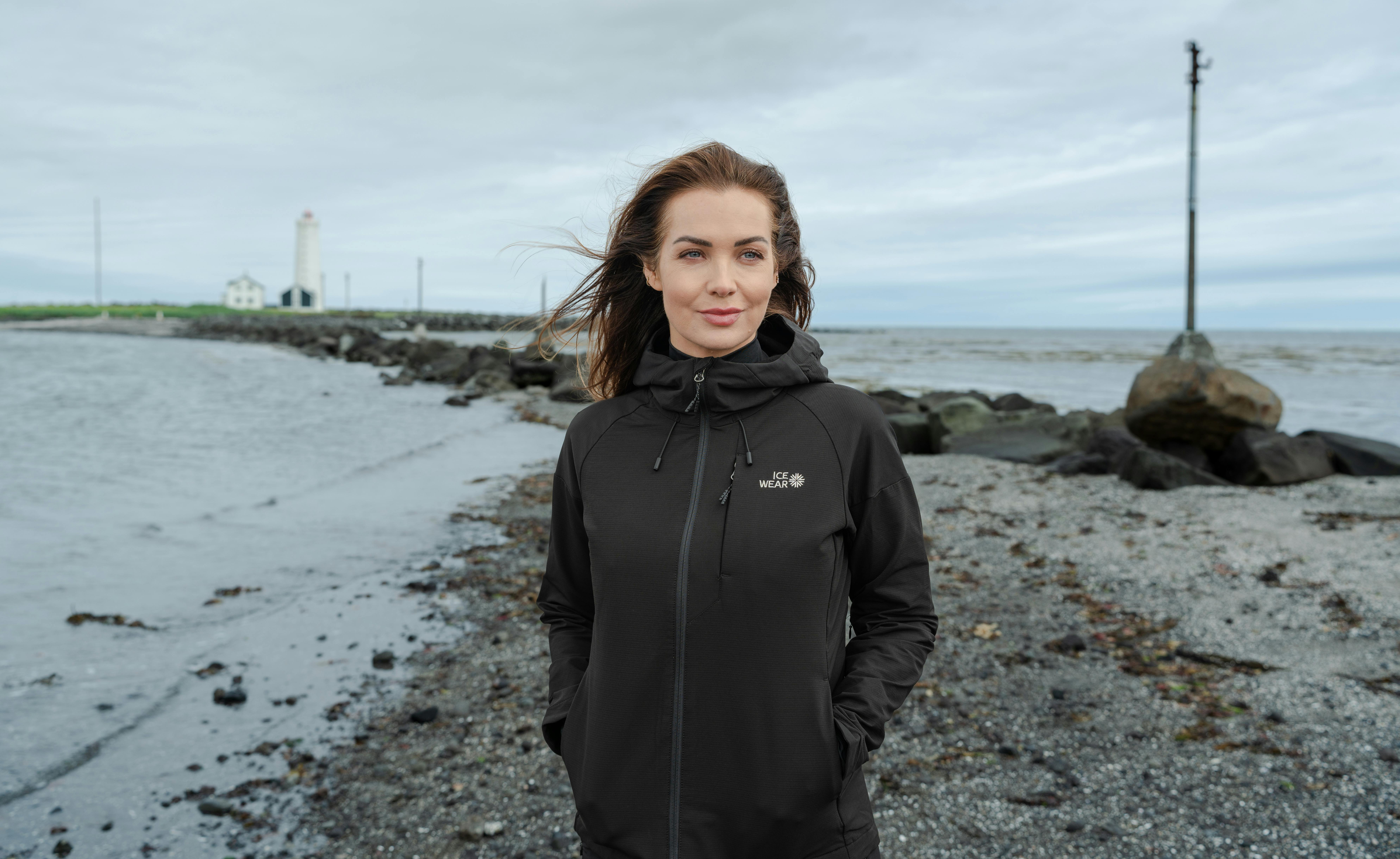 woman walking on the beach and lighthouse behind her