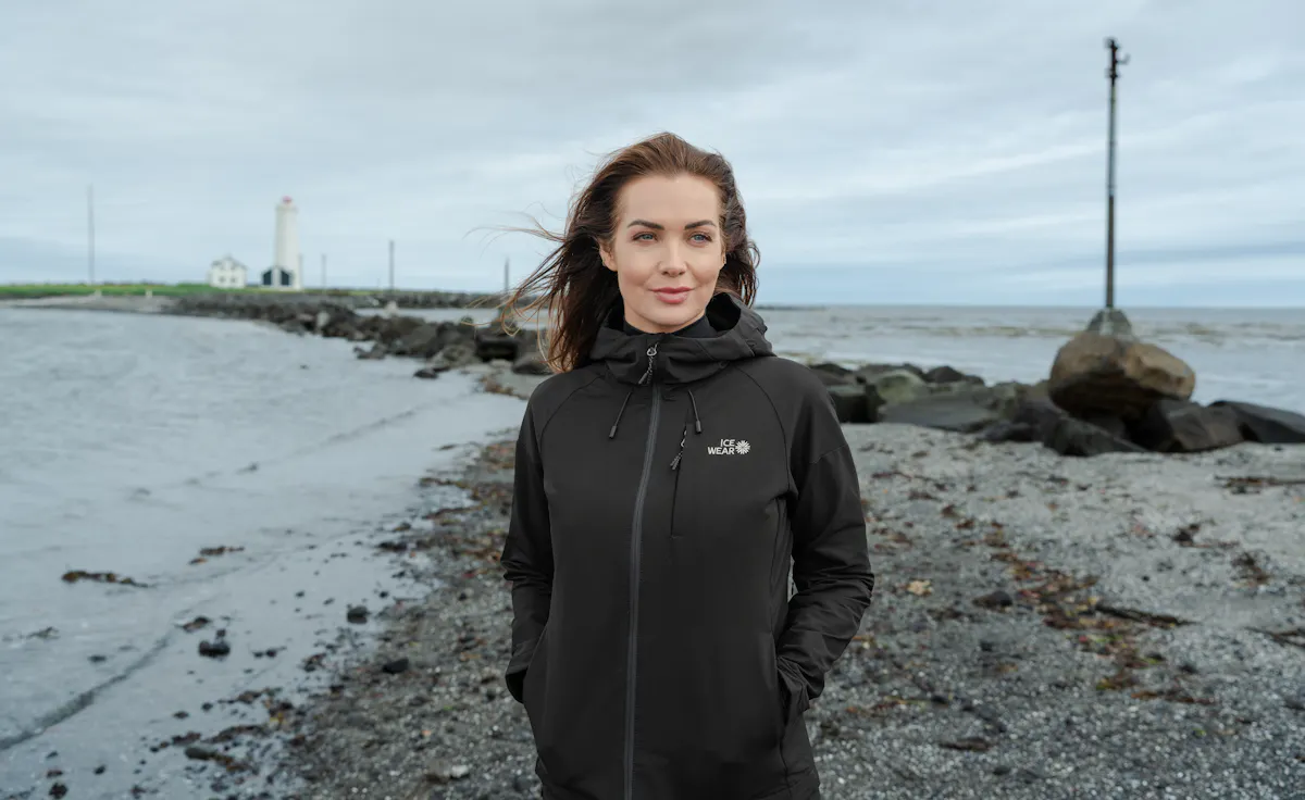 woman walking on the beach and lighthouse behind her