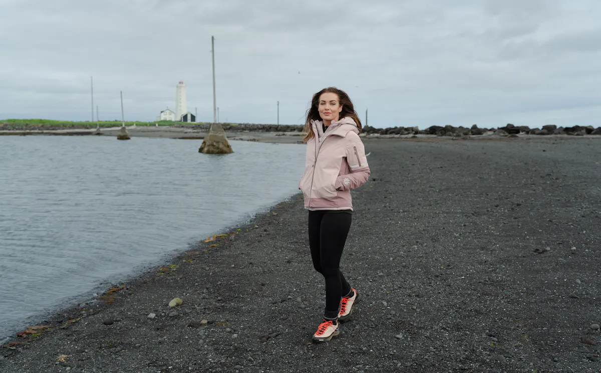 woman walking on the beach with old light house behind her