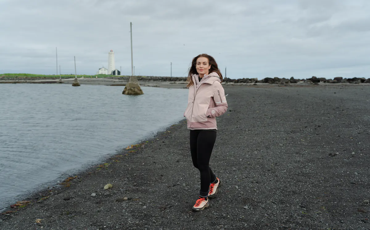 woman walking on the beach with old light house behind her