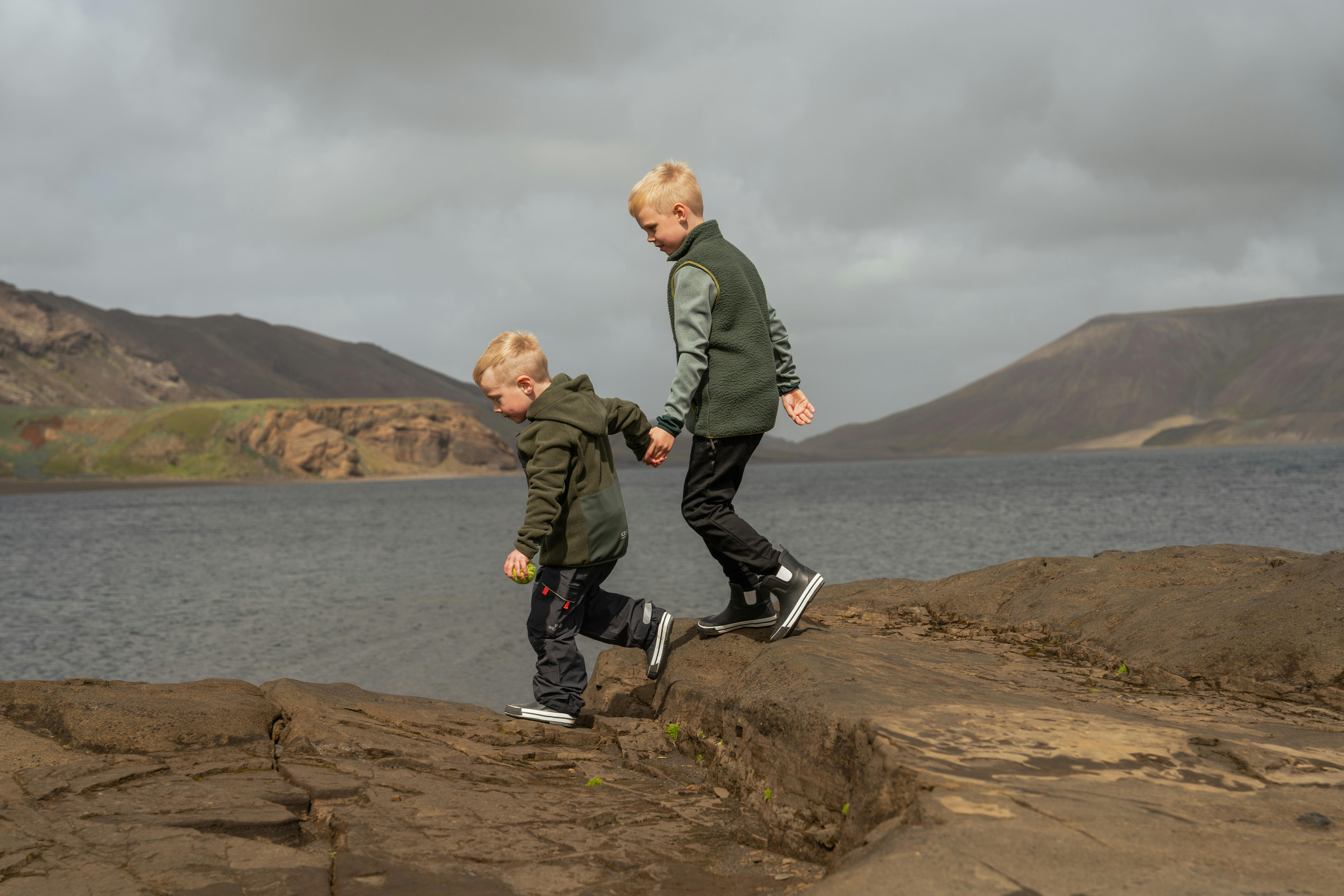 Jungs, die auf Felsen an einem See spazieren