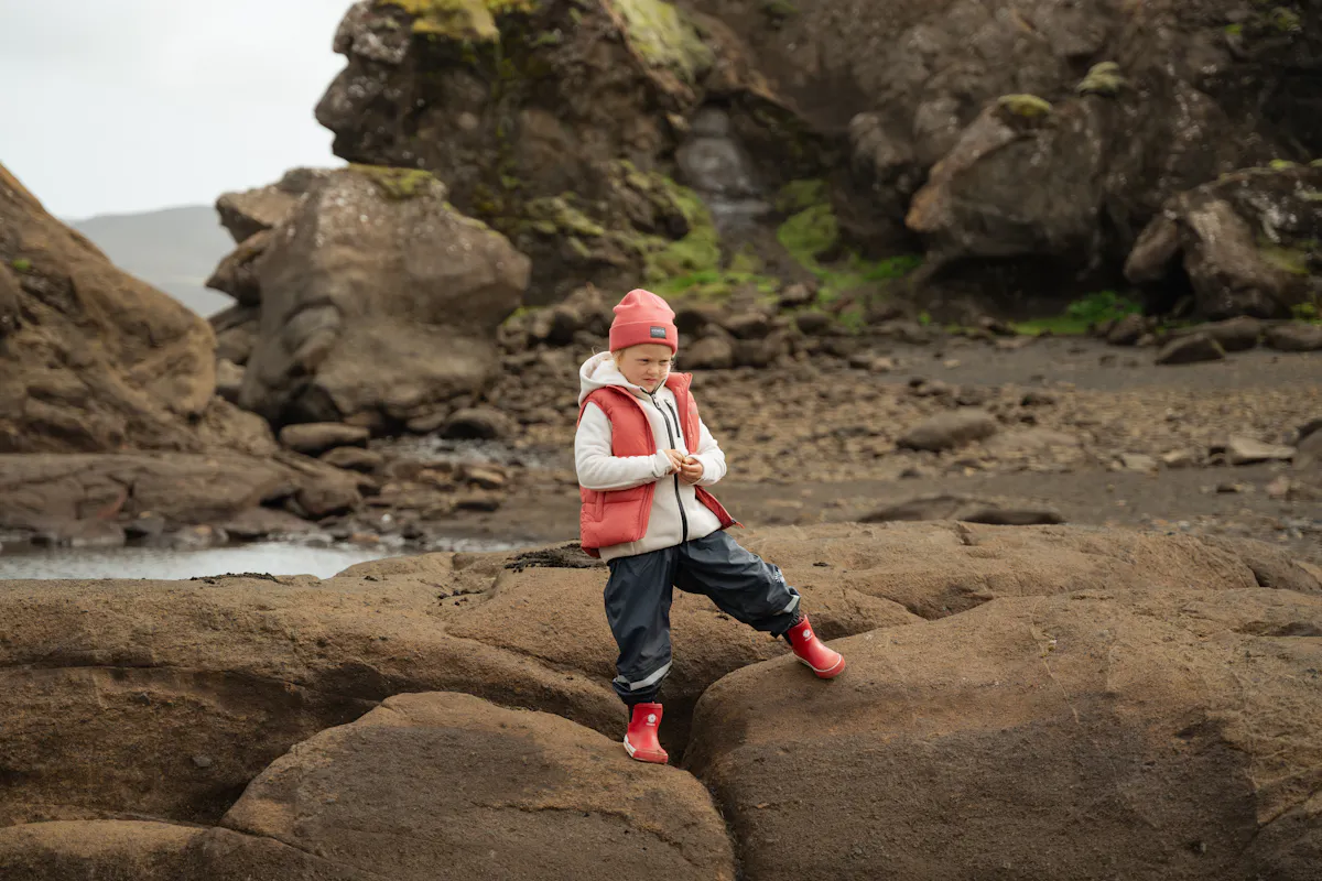 boy standing on cliff next to lake