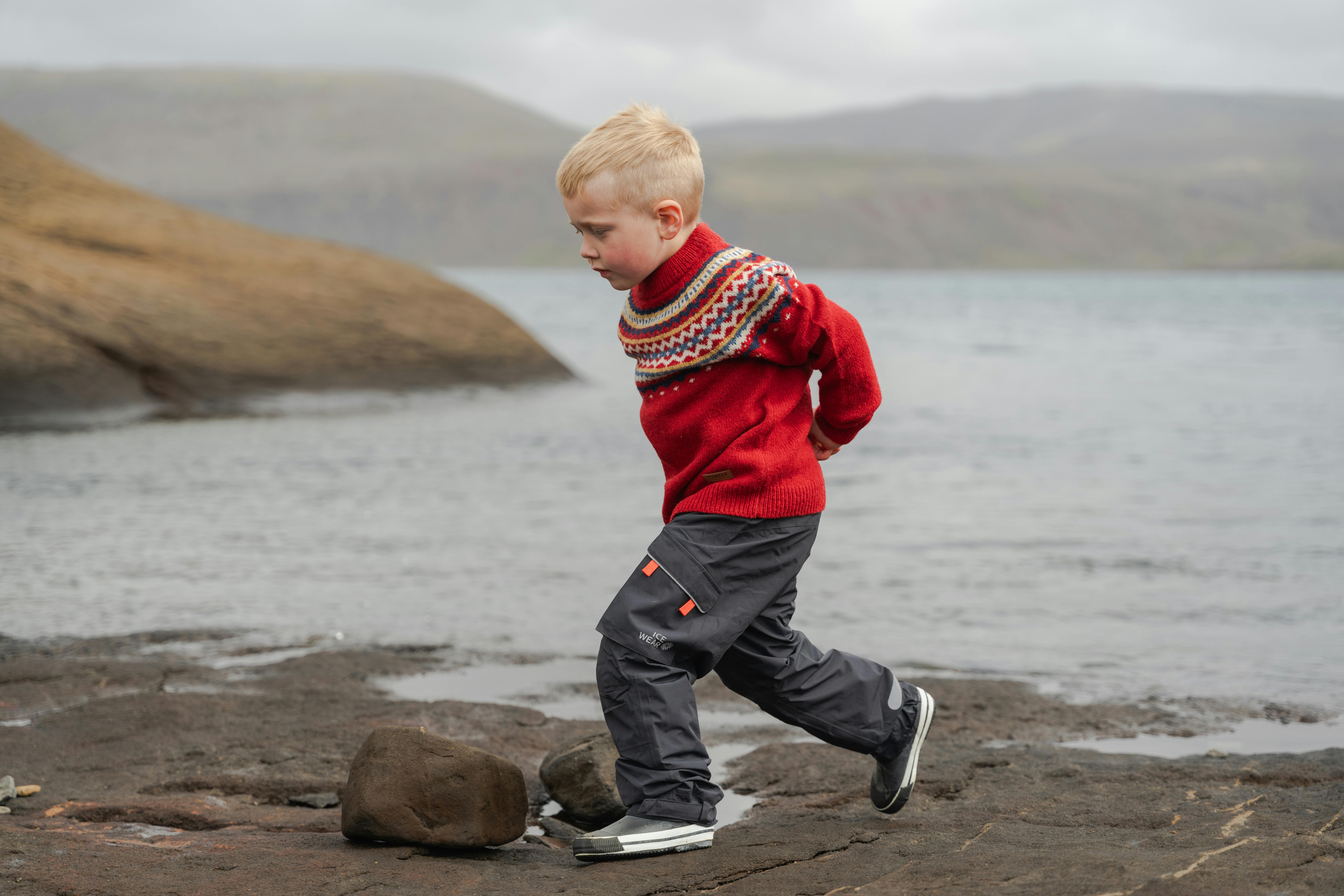 Boy running on a cliff next to a lake