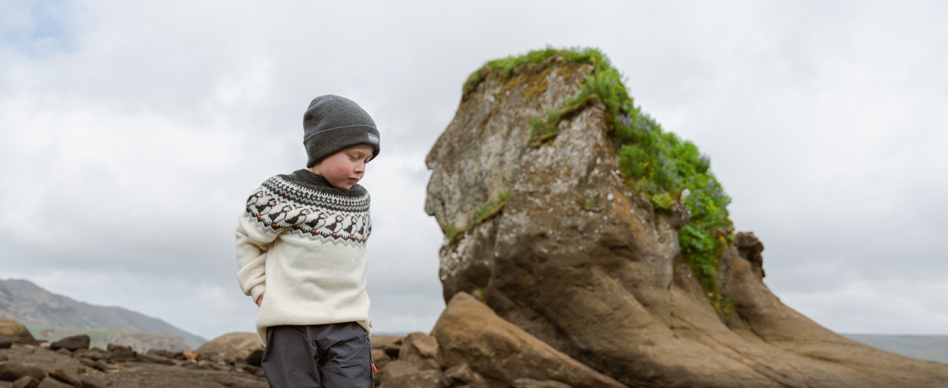 boy walking in a lake next to big cliff