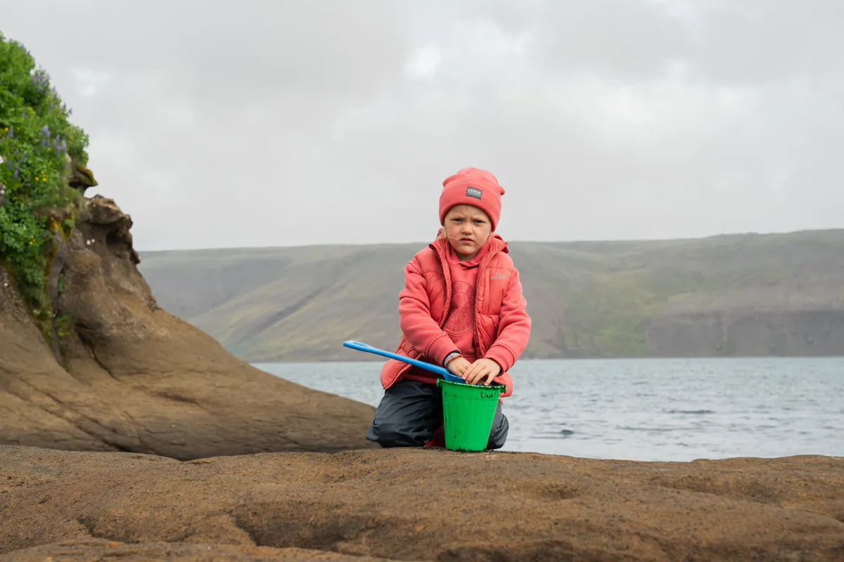 Junge schaufelt Sand in Eimer