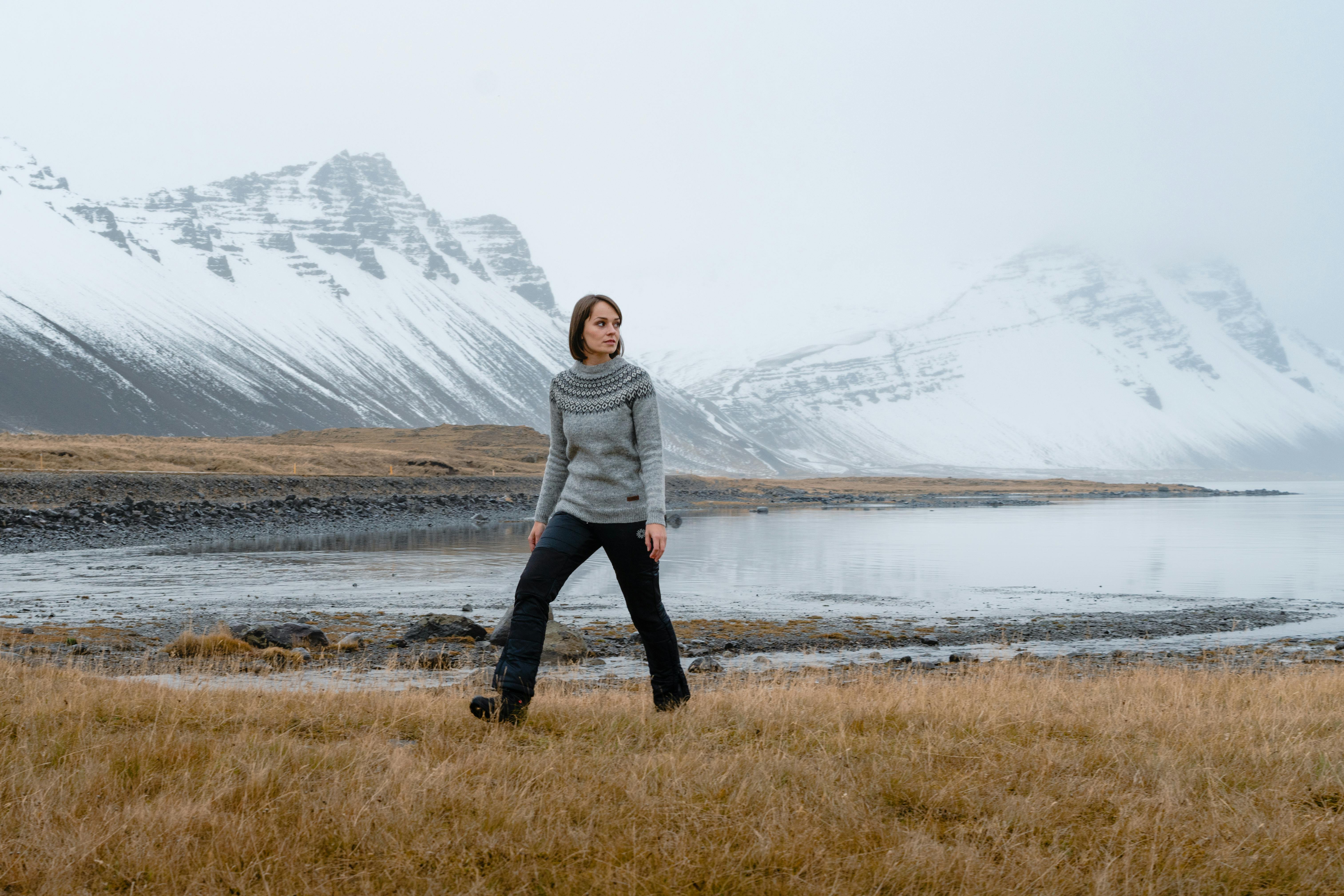 woman walking, the sea and high mountain behind her