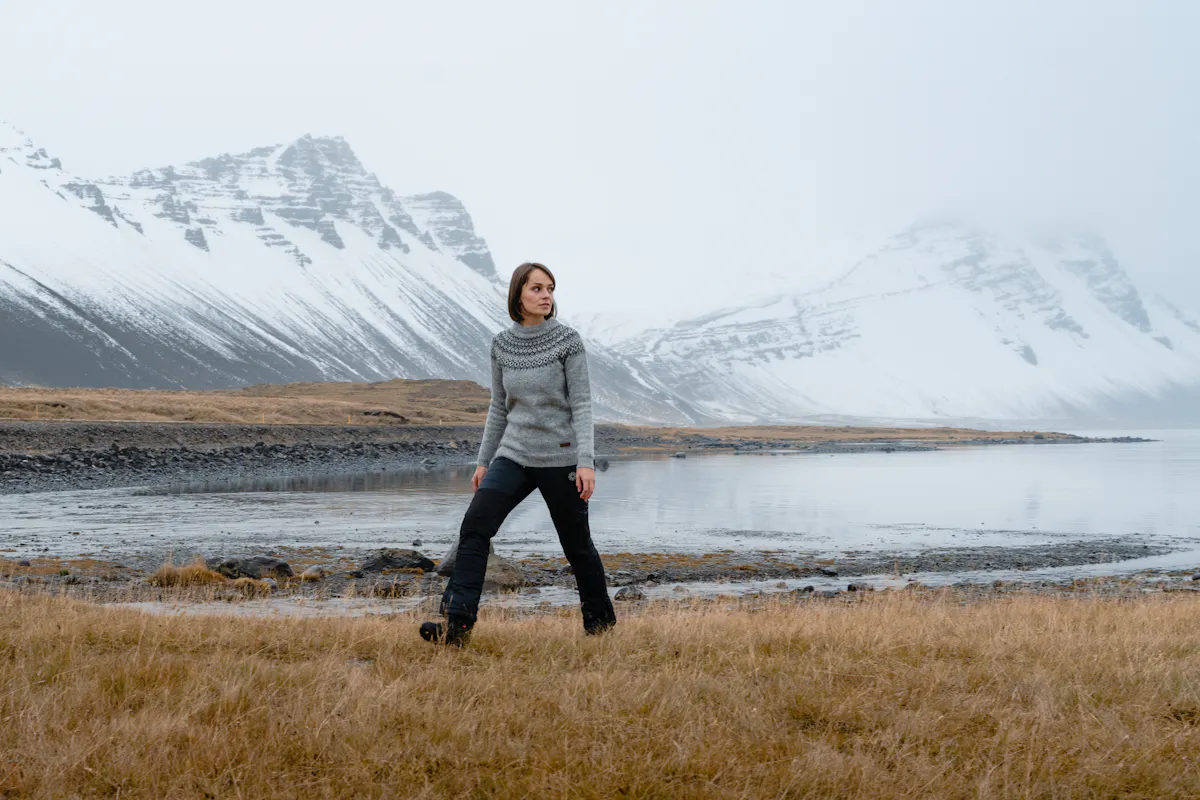 woman walking, the sea and high mountain behind her