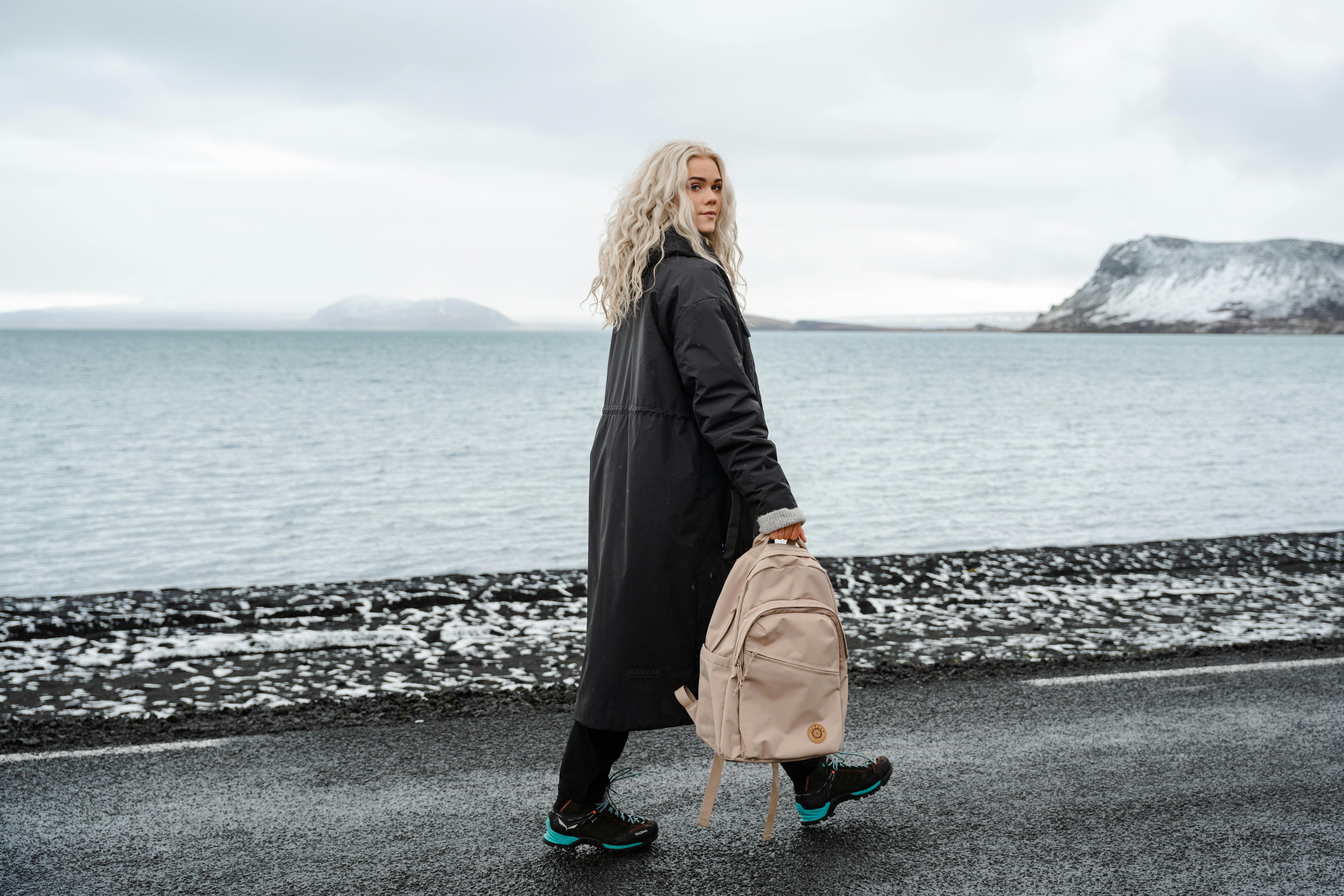woman with backpack walking on the road
