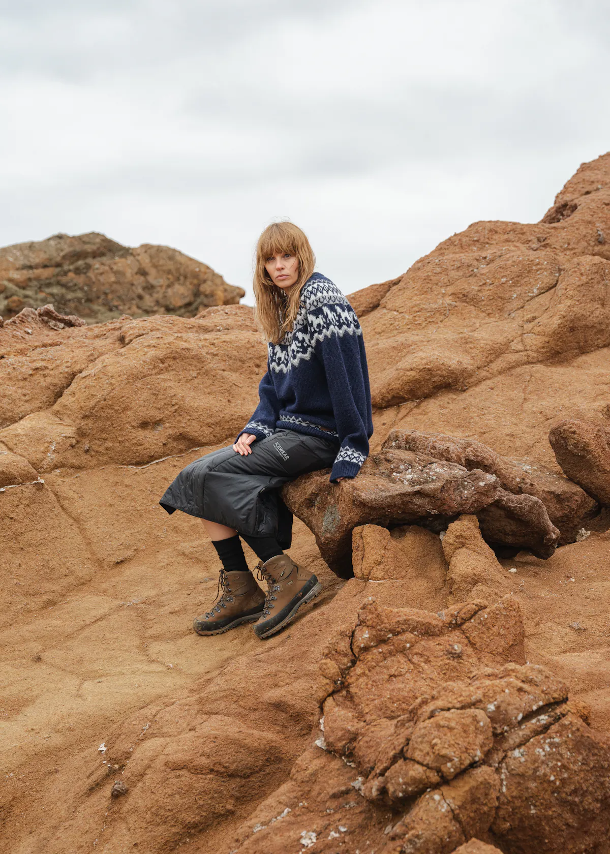 Frau sitzt auf einer Klippe