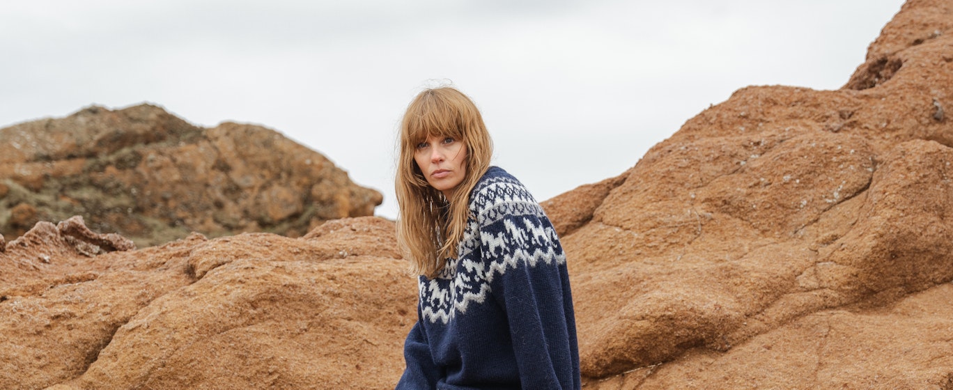 Frau sitzt auf einer Klippe