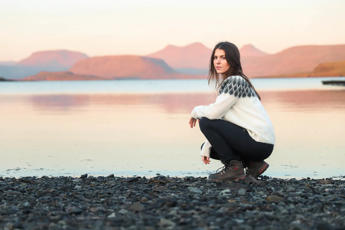 woman at rocky beach and mountain behind her