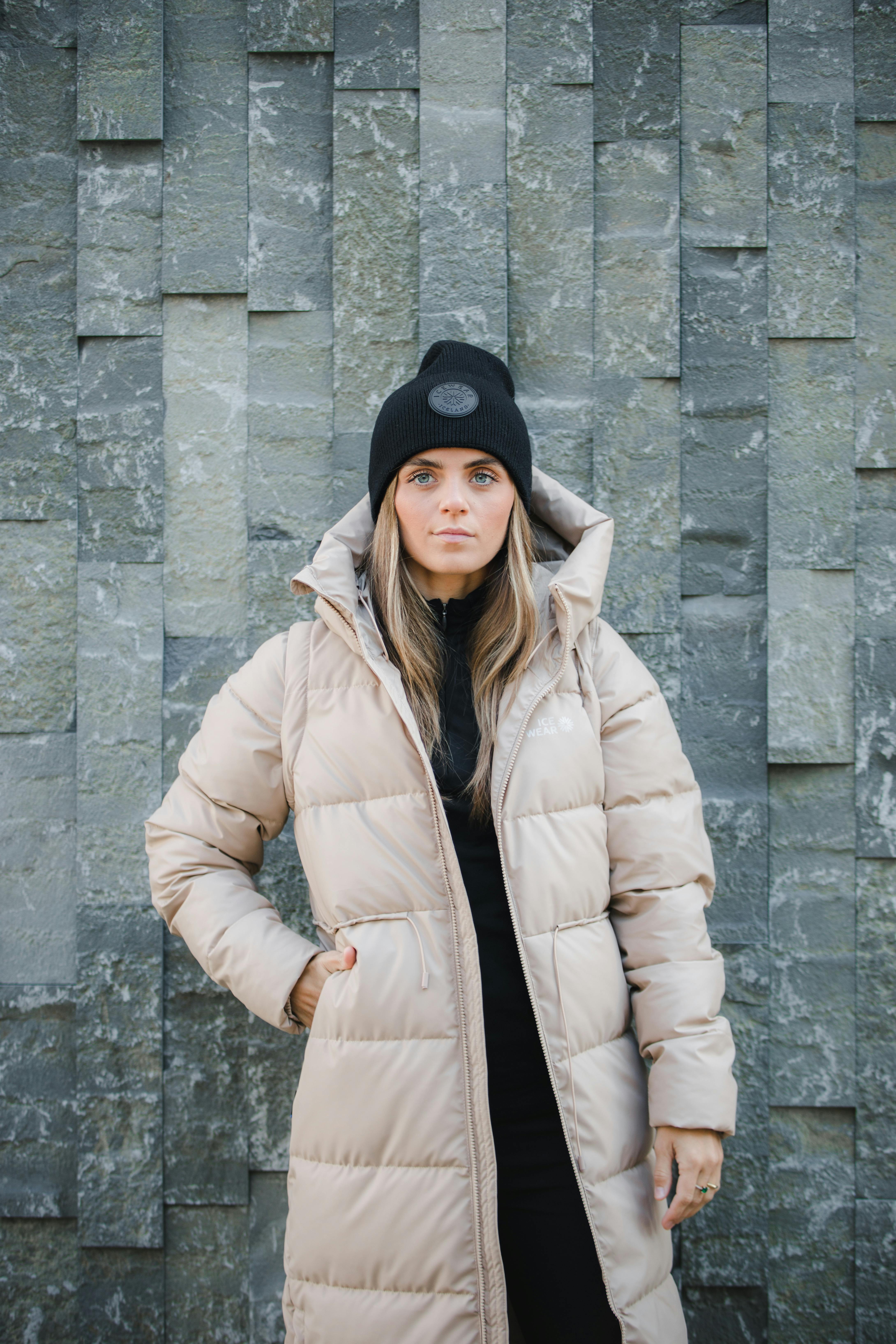 Frau steht an einer Steinmauer