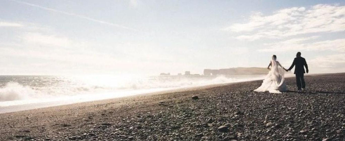 Brides and grooms walk on a black beach