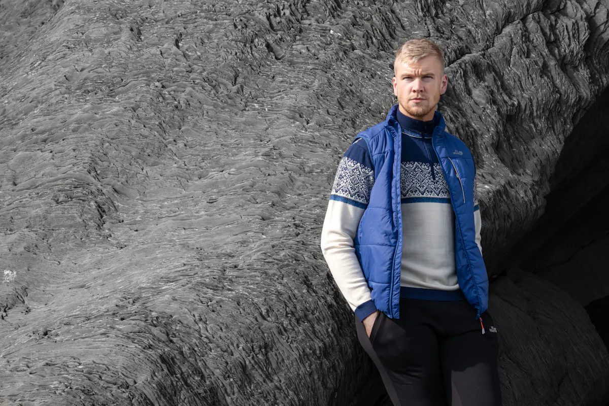 man wearing norwegian sweater standing next to a cliff