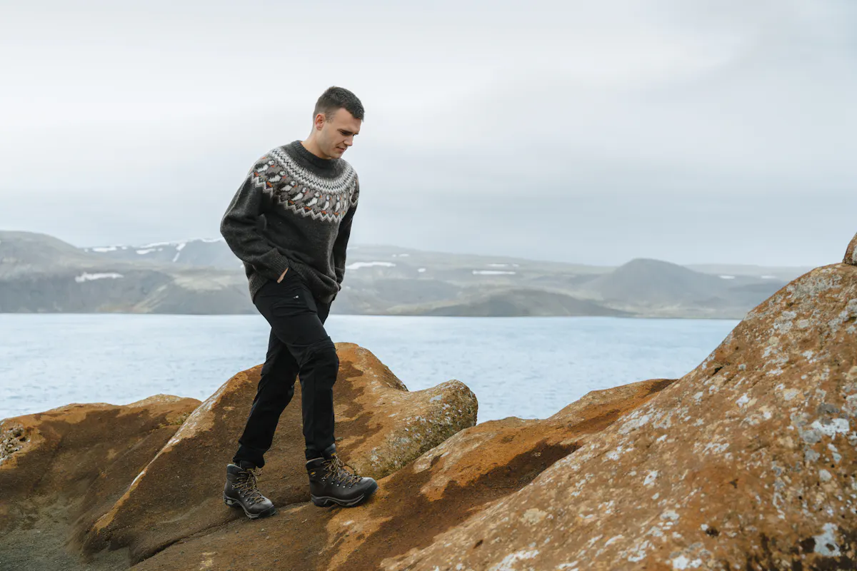 man hiking on a cliff next to sea