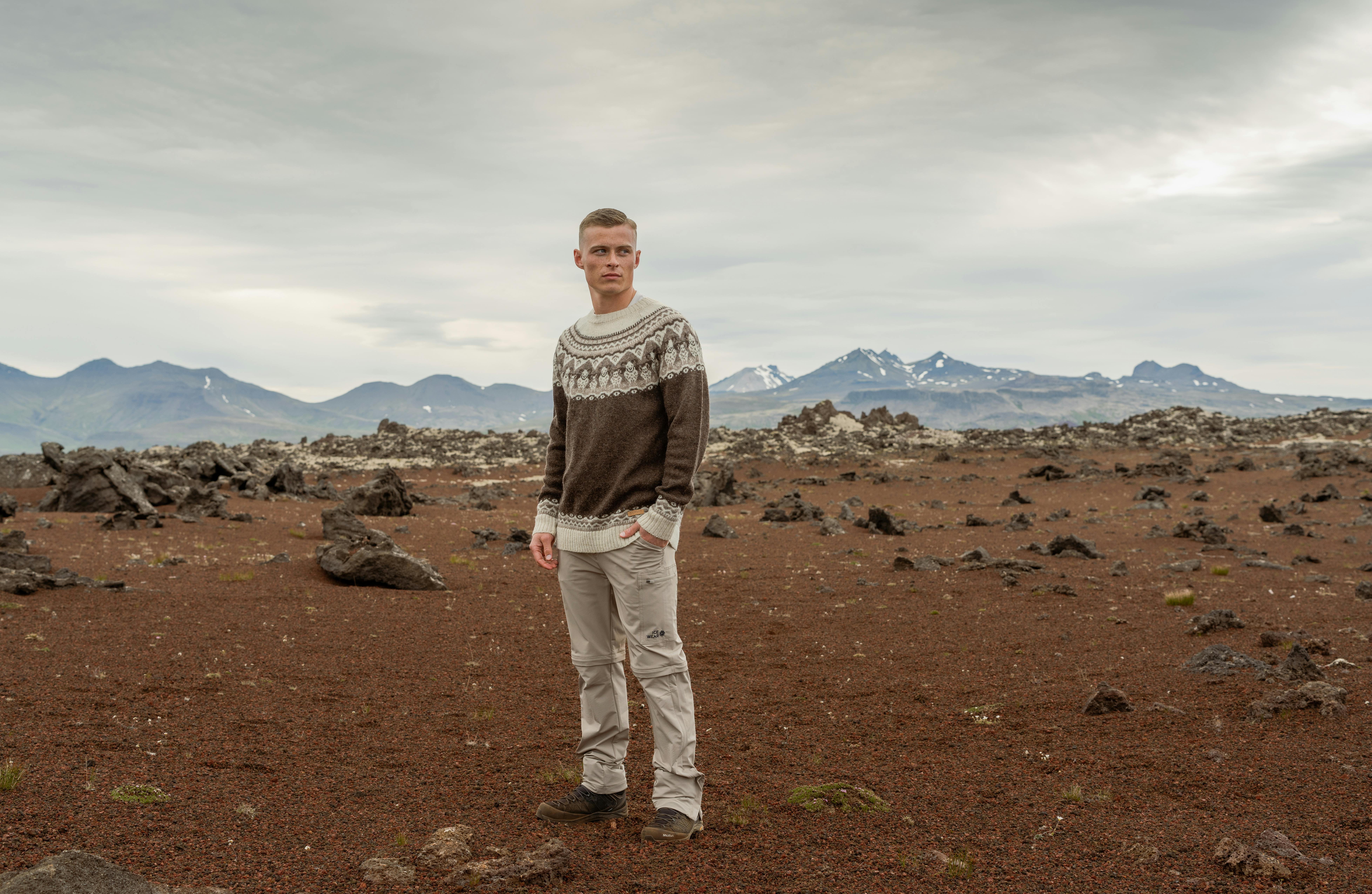 man in sandy lava nature and mountain behind him